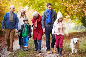 Multl Generation Family Walking Along Autumn Path With Dog