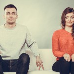 Shy woman and man sitting on sofa